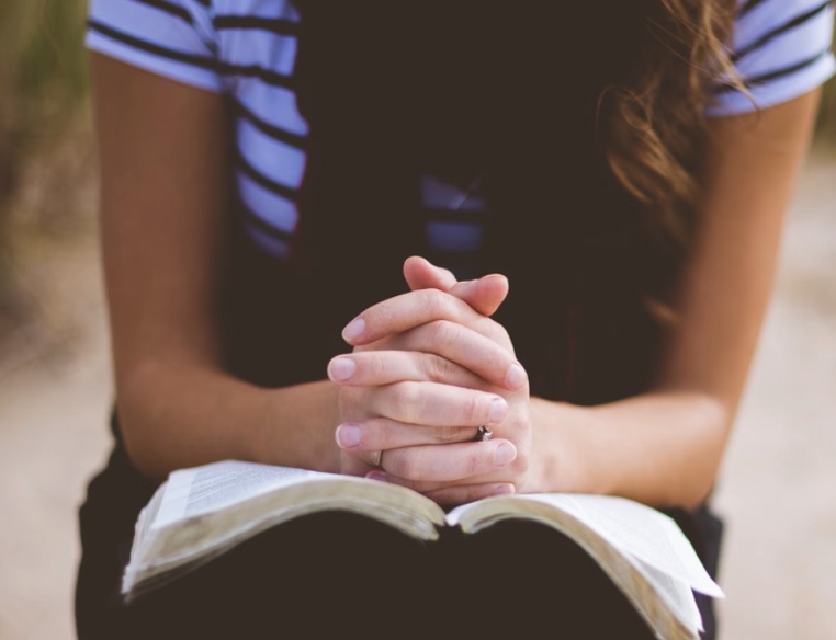 praying hands on a Bible
